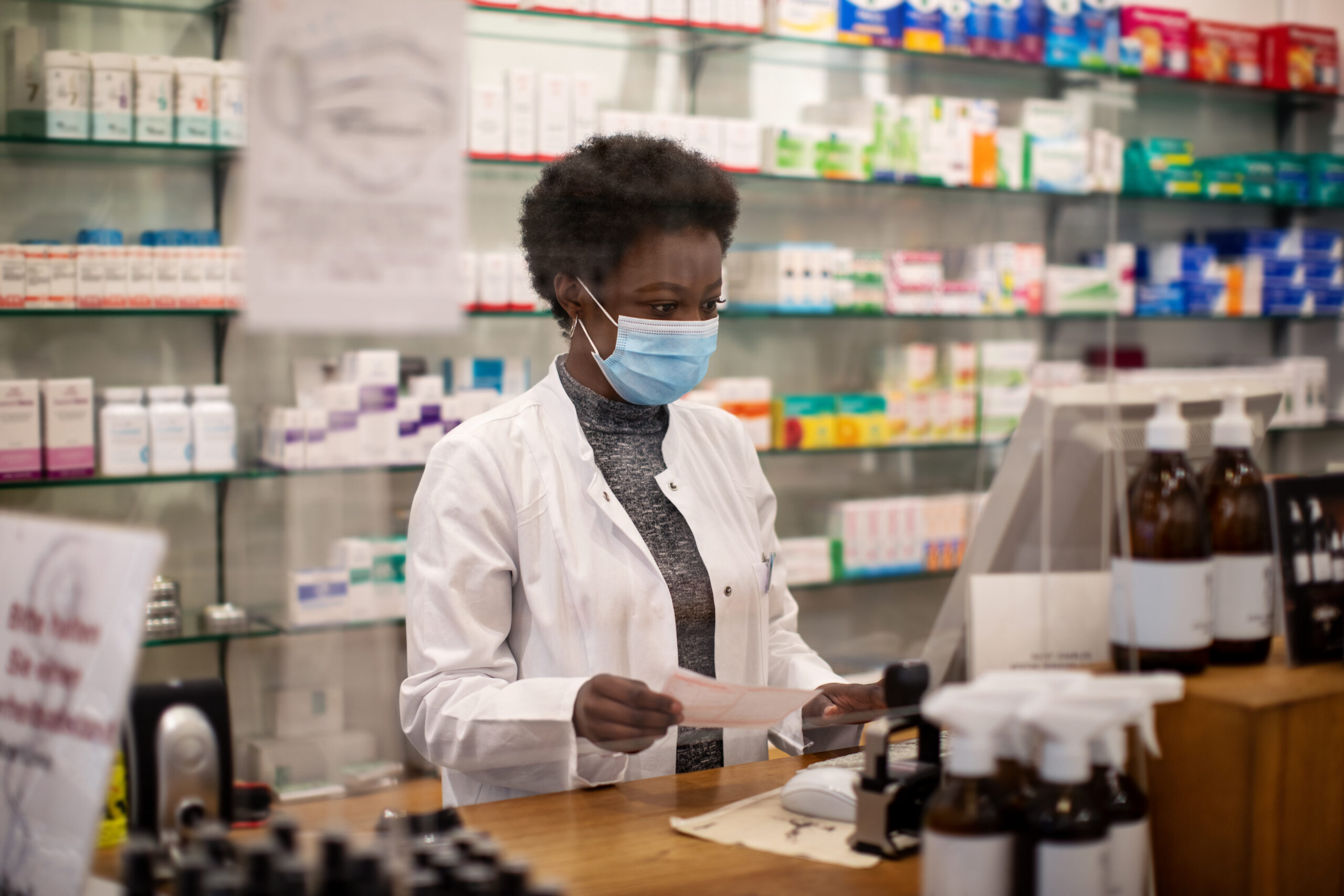 Woman pharmacist with face mask working in a drug store