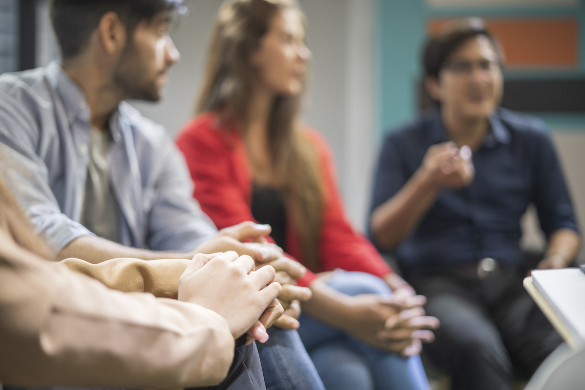 Young males and females are sharing ideas during group therapy.Support group gathering for a meeting.