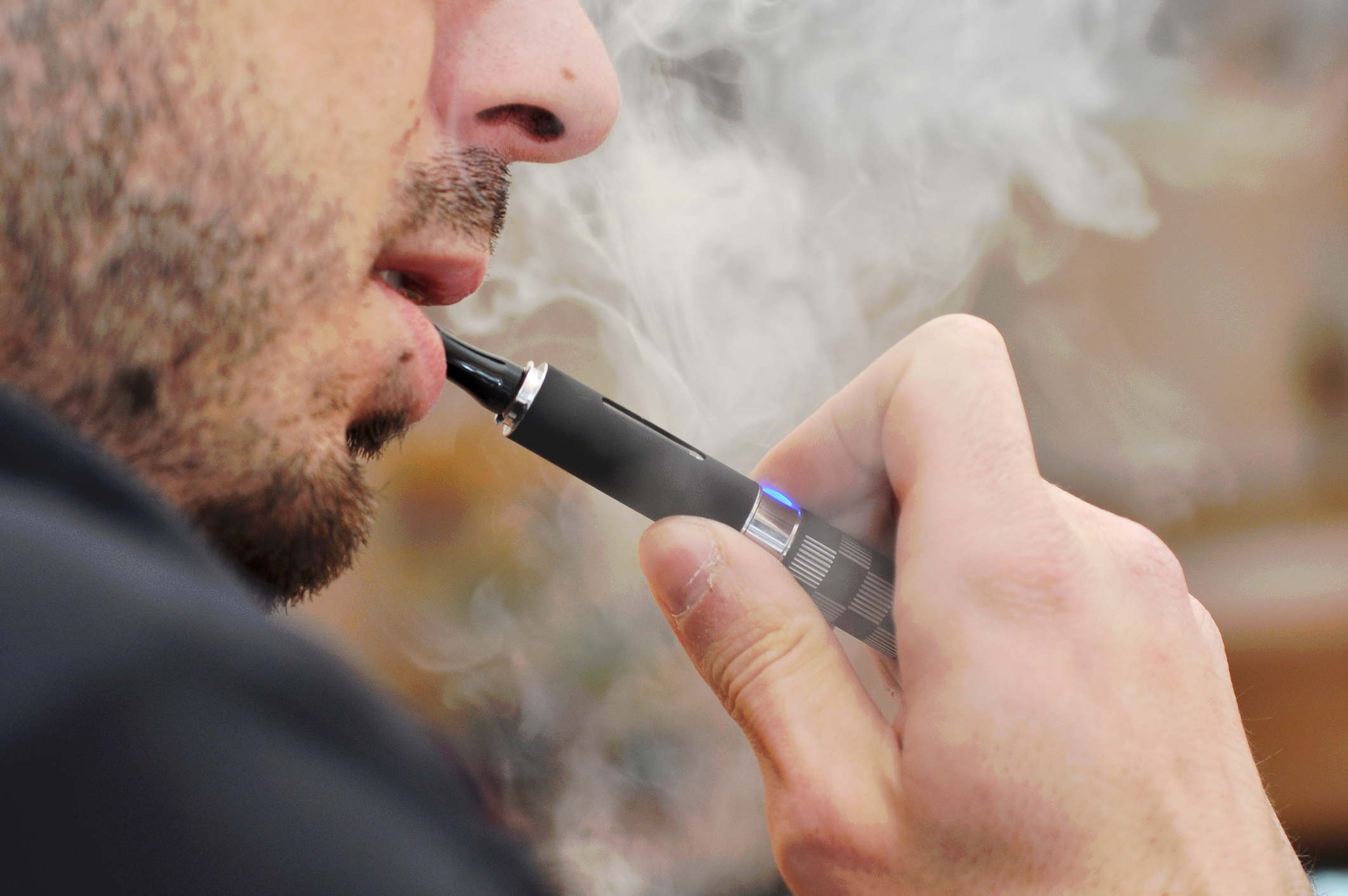 Male outside vaping from an electronic cigarette with smoke