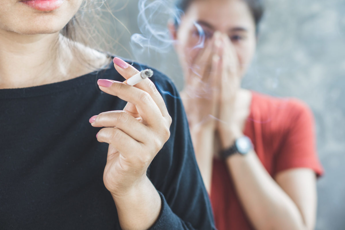 Woman smoking cigarette and woman inhaling secondhand smoke