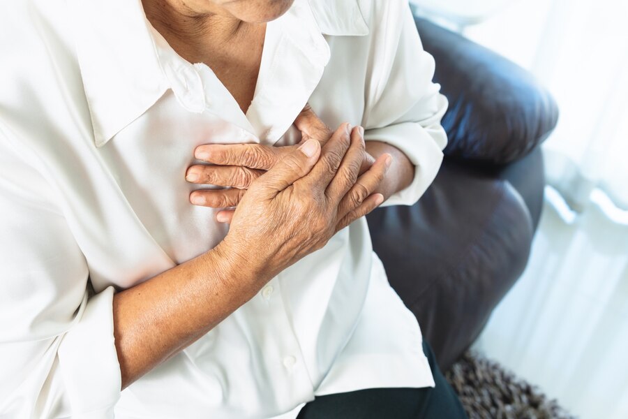 Woman in white shirt grabbing chest due to lung pain