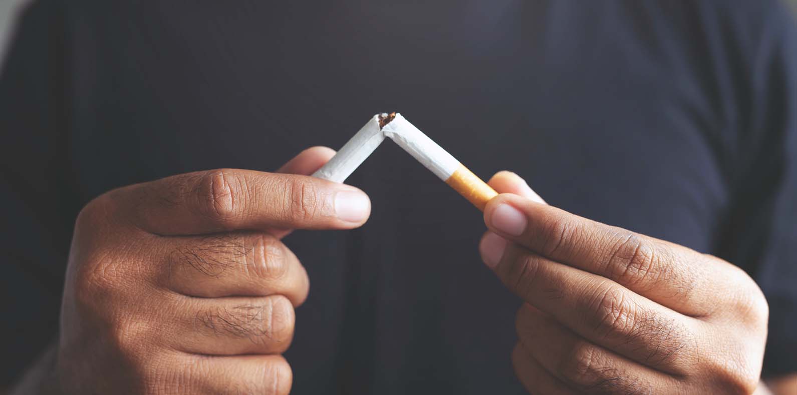 A smoker breaks a cigarette in half to symbolize quitting smoking.