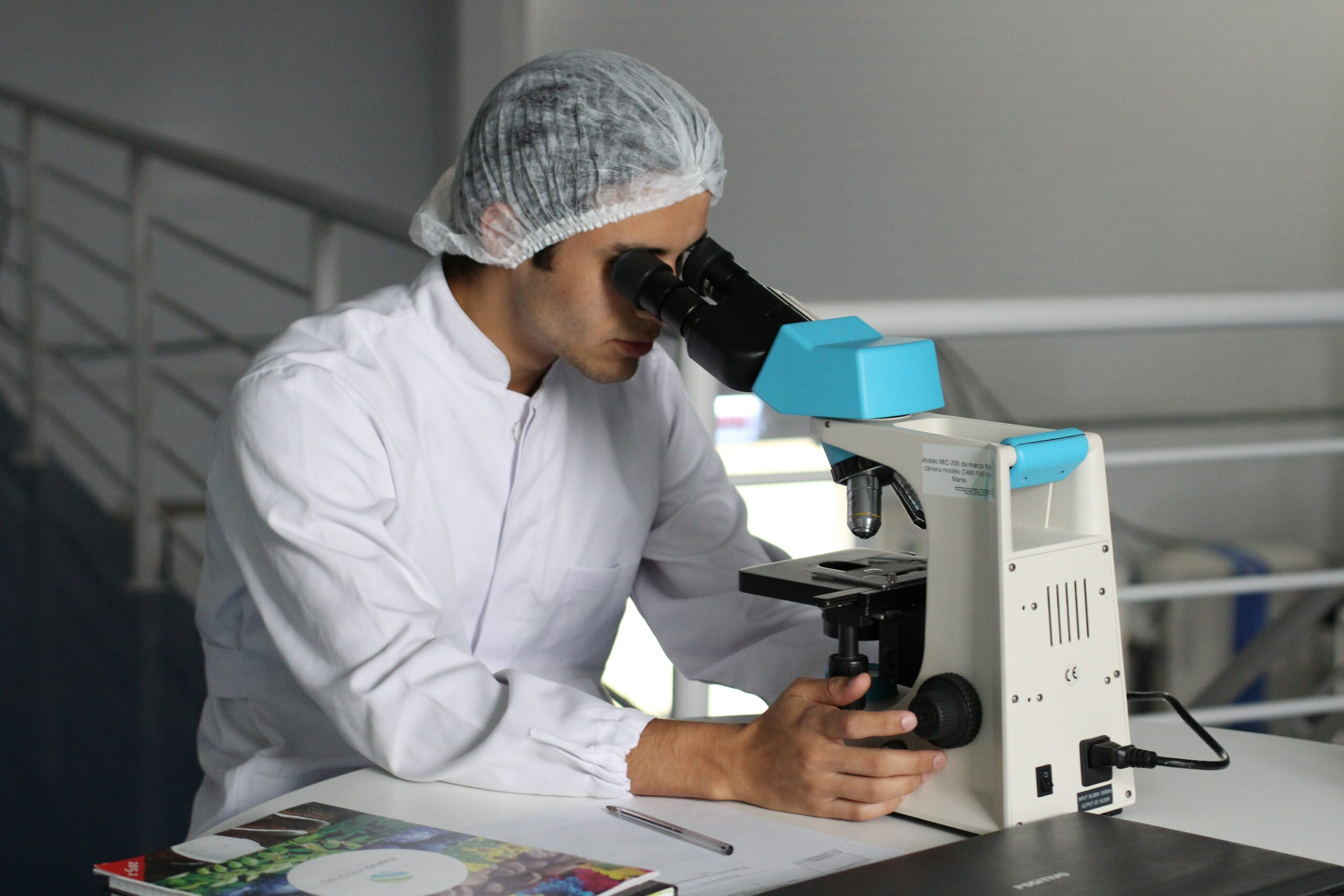 Doctor in lab attire looking into microscope during scheduled lung cancer clinical trials.