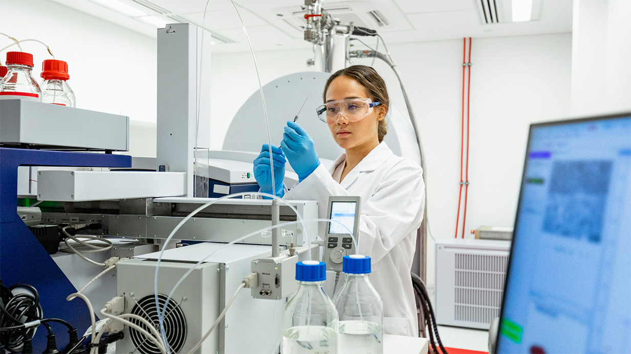 Woman in white lab coat holding a lung cancer biomarkers test in a medical laboratory.