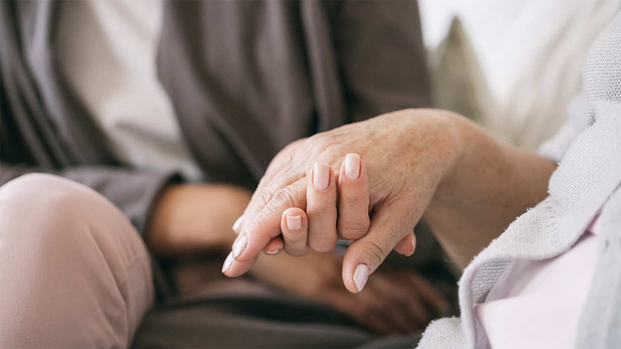 Woman holding hand with cancer patient