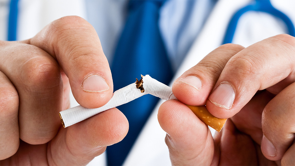 Doctor in suit and white coat breaking cigarette with hands