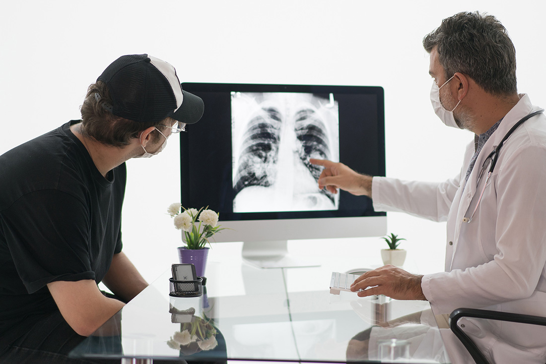 Doctor showing patient an x-ray image of the lungs and chest cavity in stage 3 mesothelioma.