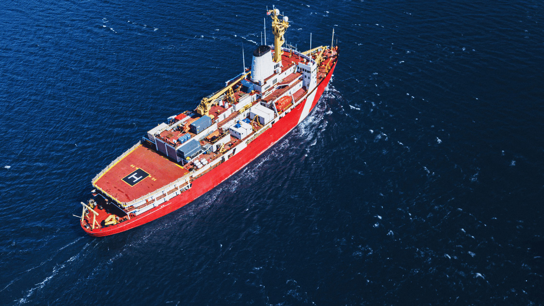 A coast guard military icebreaker navigates blue choppy waters