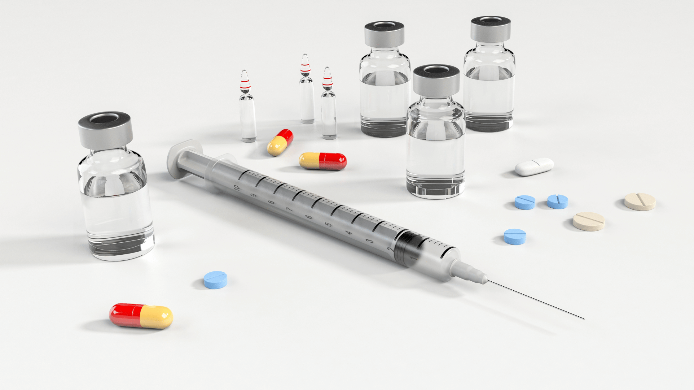 Adagrasib alongside a needle, pills, and vials scattered on white table