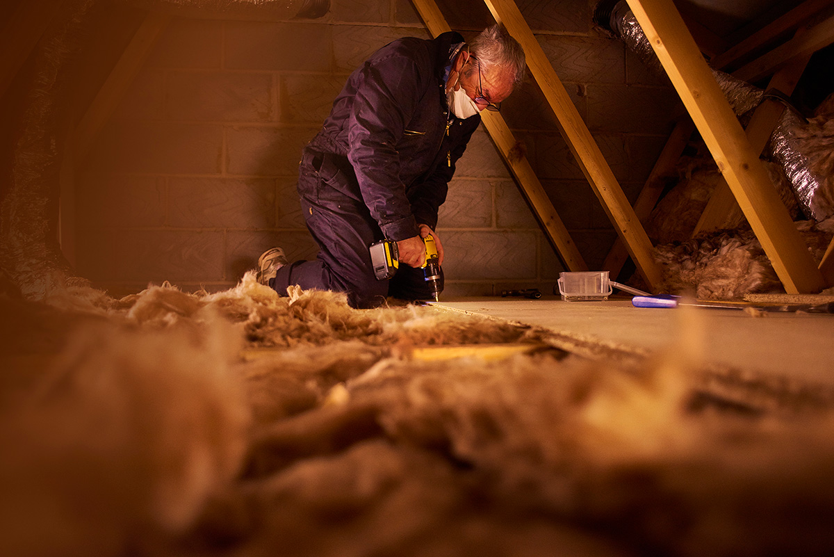 Carpenters and asbestos insulation in an attic.