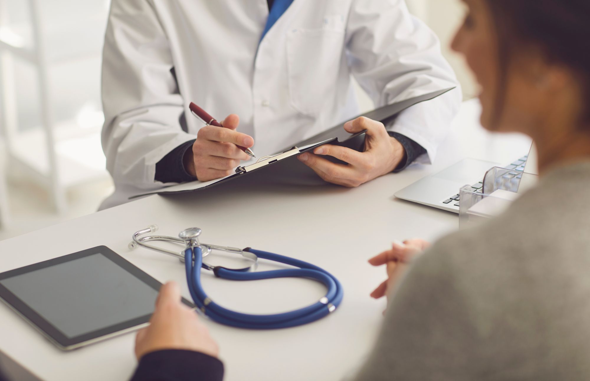 A girl asking her specialist questions about mesothelioma. They are sitting across from each other at a desk.