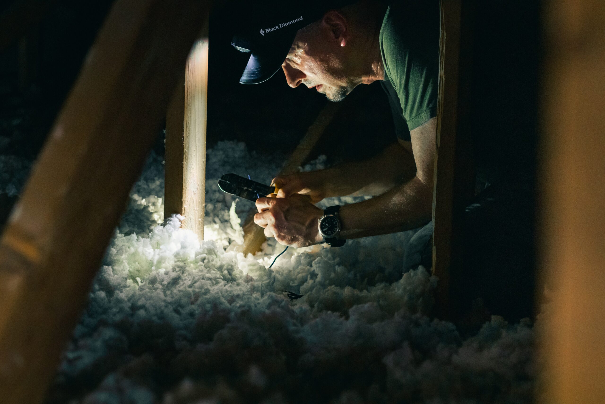 A man working with asbestos insulation in an attic.