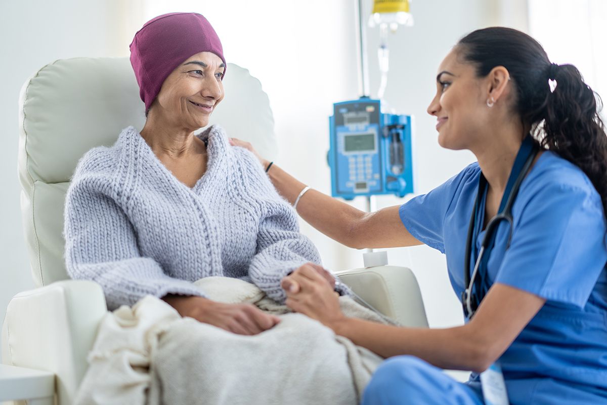 Female cancer patient discussing immunotherapy vs. chemotherapy with nurse at doctor's office