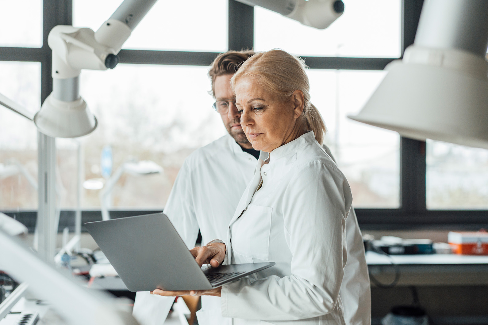 A doctor and their colleague look over a computer while in a lab.