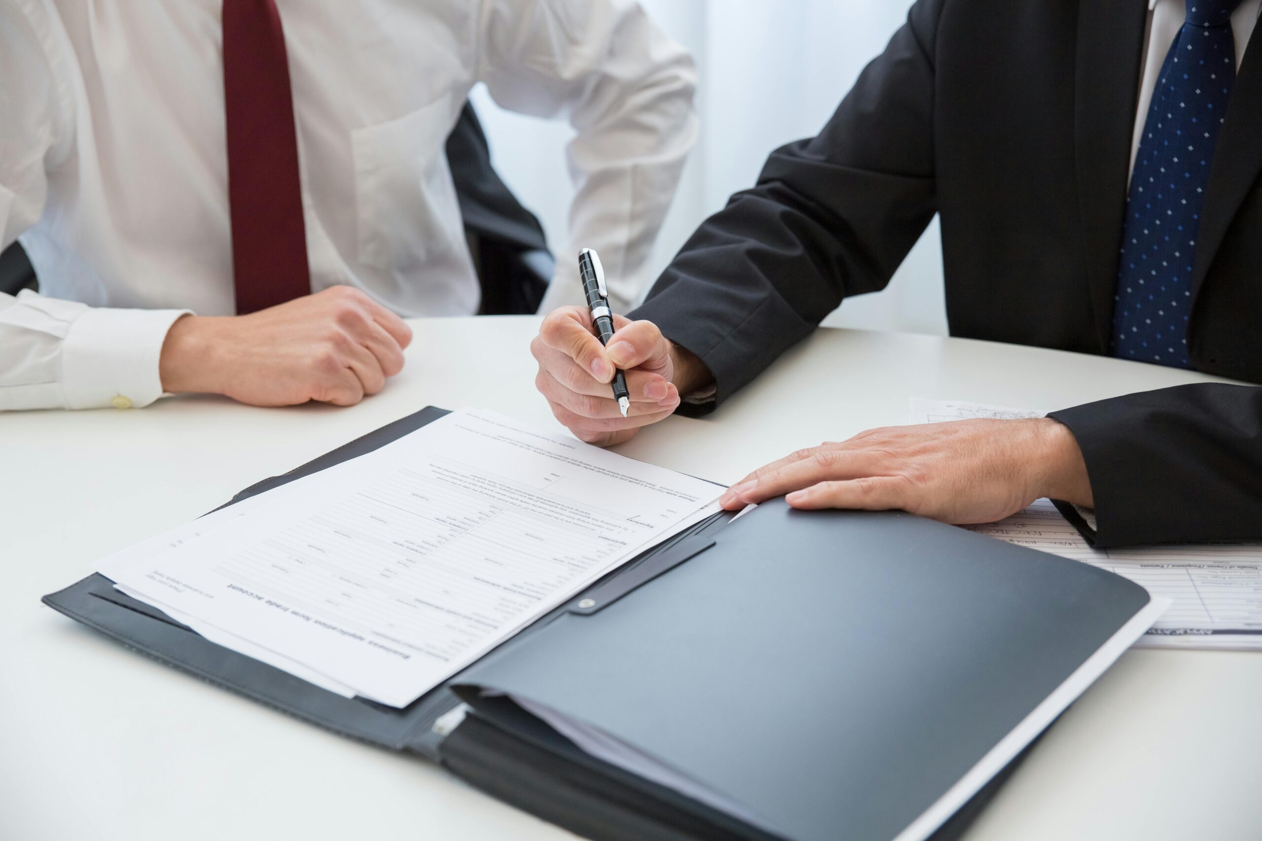 A Person in a Black Suit Holding a Pen Near the Asbestos Trust Funds Document on the Table