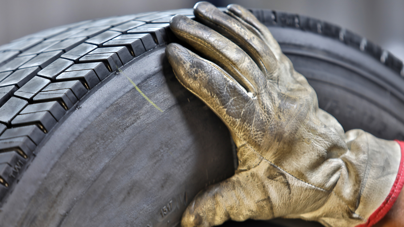 Retread manufacturing worker touching finished tire.