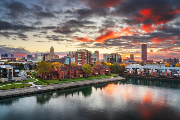 Buffalo, New York skyline at sunset, showing historic industrial district known as Asbestos Alley, with aging buildings containing legacy asbestos contamination